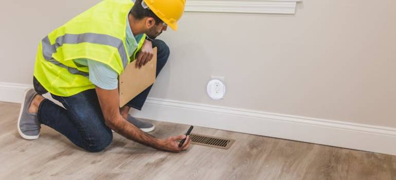 Inspector checking home vent with flashlight.